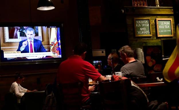 Clientes siguen el mensaje del Rey en un bar de Barcelona./Afp