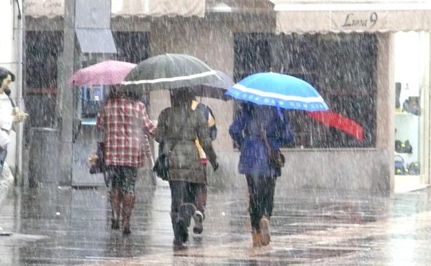 Un grupo de personas camina bajo la lluvia en la Calle Ancha de León capital./