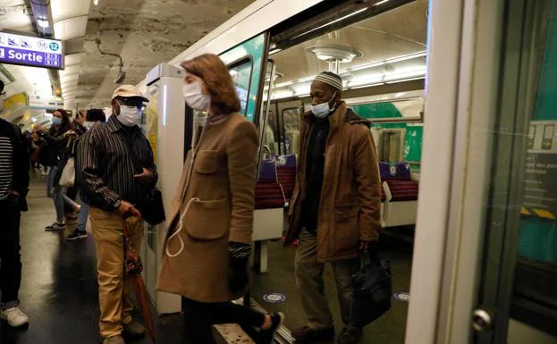 Viajeros en una estación de metro de París se trasladan protegidos con la mascarilla obligatoria./AFP