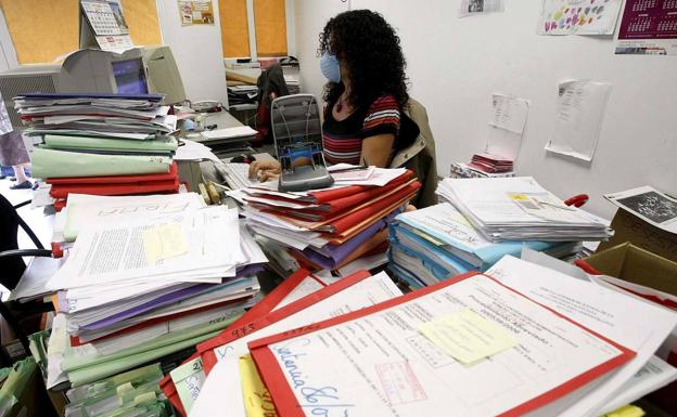 Una funcionaria de la Administración de Justicia junto a decenas de expedientes pendientes de resolver./Efe