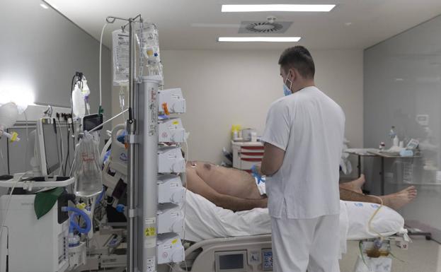 Un sanitario atiende a un paciente ingresado en la UCI del Hospital Isabel Zendal de Madrid./Eduardo Parra / E. P.