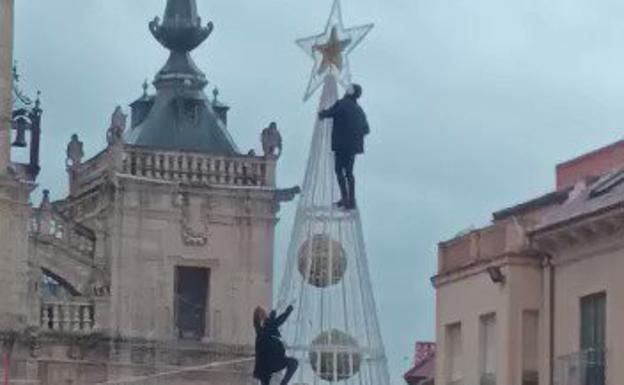 Dos personas escalan el árbol de Navidad de Astorga