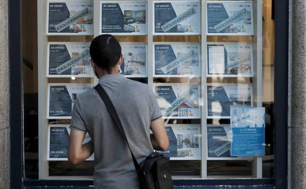 Un joven busca viviendas de alquiler o venta en el escaparate de una inmobiliaria de Madrid./O. Chamorro
