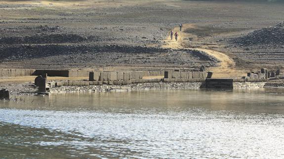 El bajo nivel de agua en el embalse de Bárcena deja al descubierto el antiguo puente del Camino Real de Carlos III